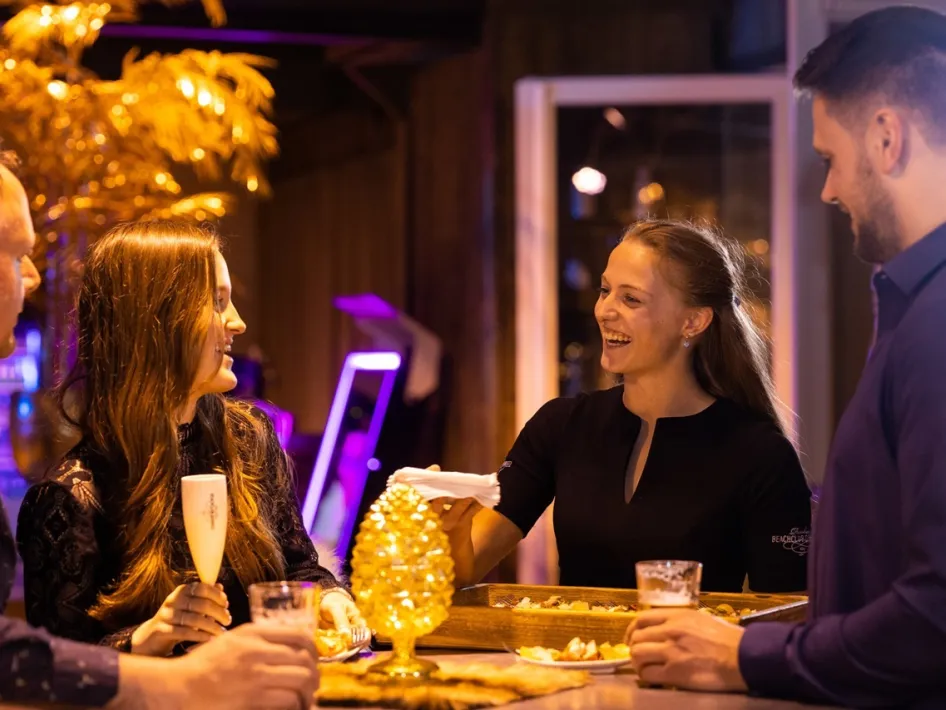 Staff member serving snacks to guests at the bar at Fun Beach – Beachclub Degreez.