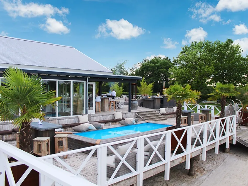 Terras van Beachclub Degreez met zwembad, ligstoelen en uitzicht op het strand.