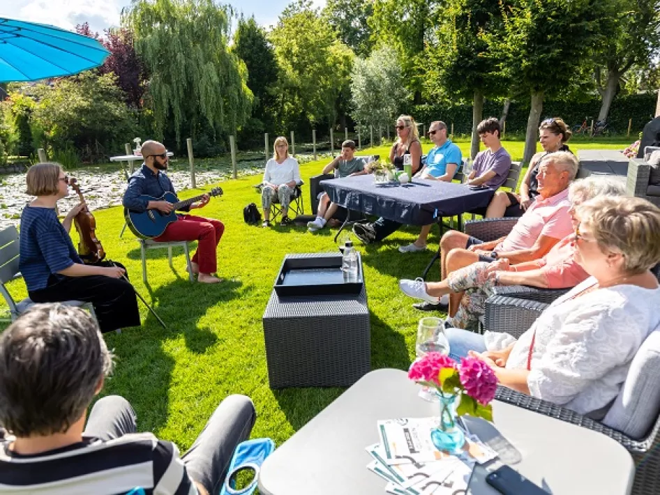 Mensen zitten in op een terras naar muziek te luisteren. 