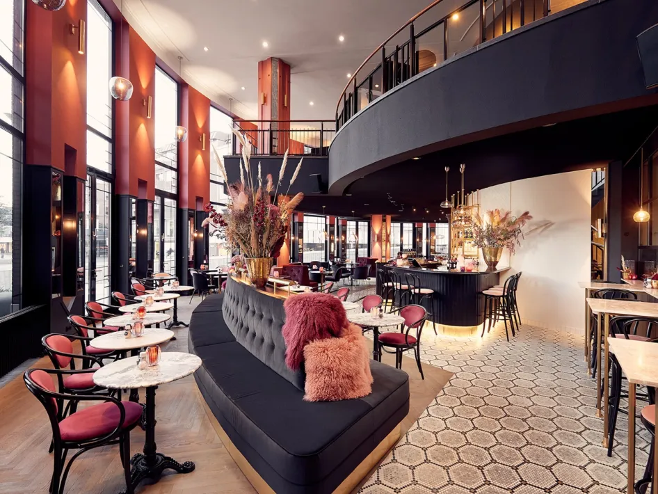 Modern en warm ingericht Cerise Grand Café met hoge ramen, stijlvolle zitplaatsen en een uitnodigende bar.