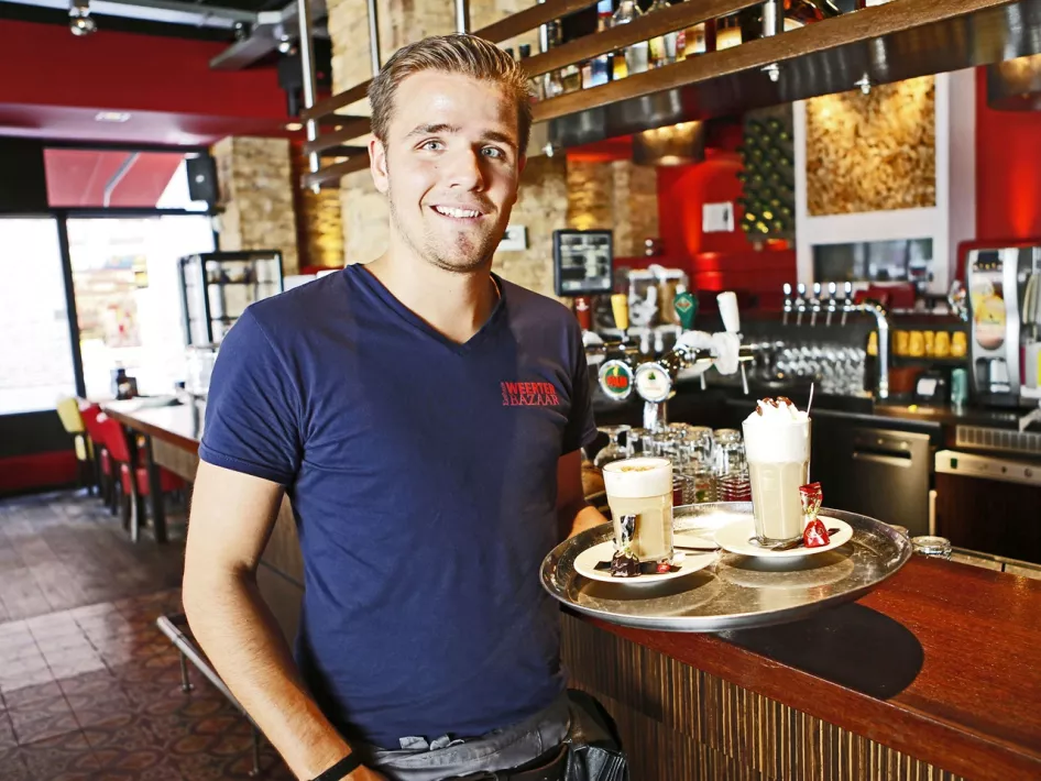 Ober van Grand Café de Weerter Bazaar met een dienblad met twee speciale koffies 