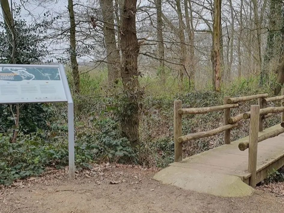 Houten brug over de gereconstrueerde tankgracht in het bos bij Reuver, onderdeel van de wandelroute Grenzgeschichten.