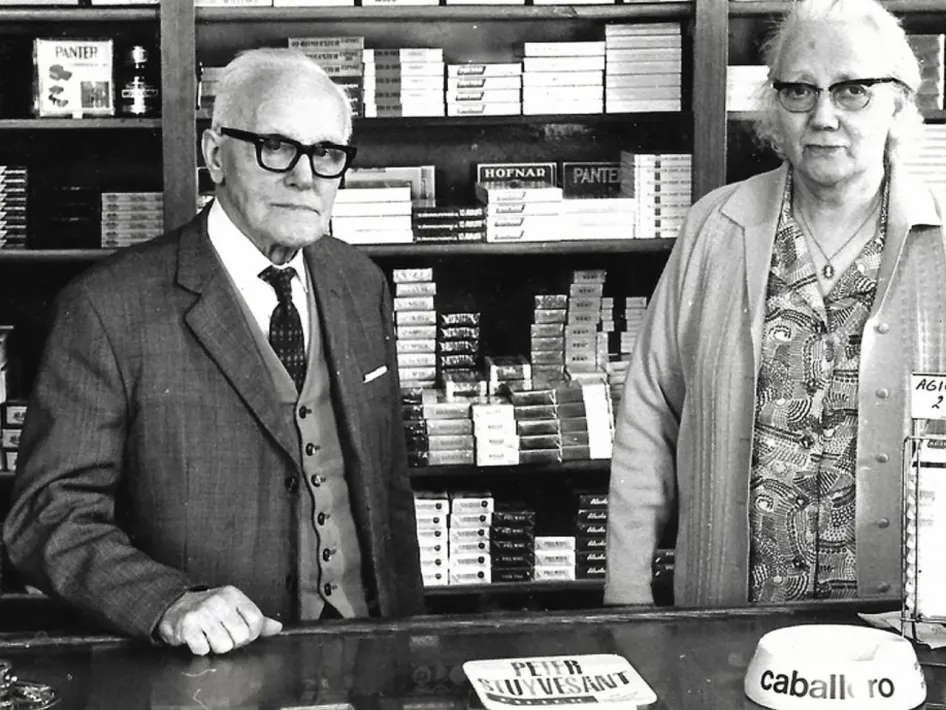 Black-and-white photo of the Vossen couple behind the counter of their shop during wartime.