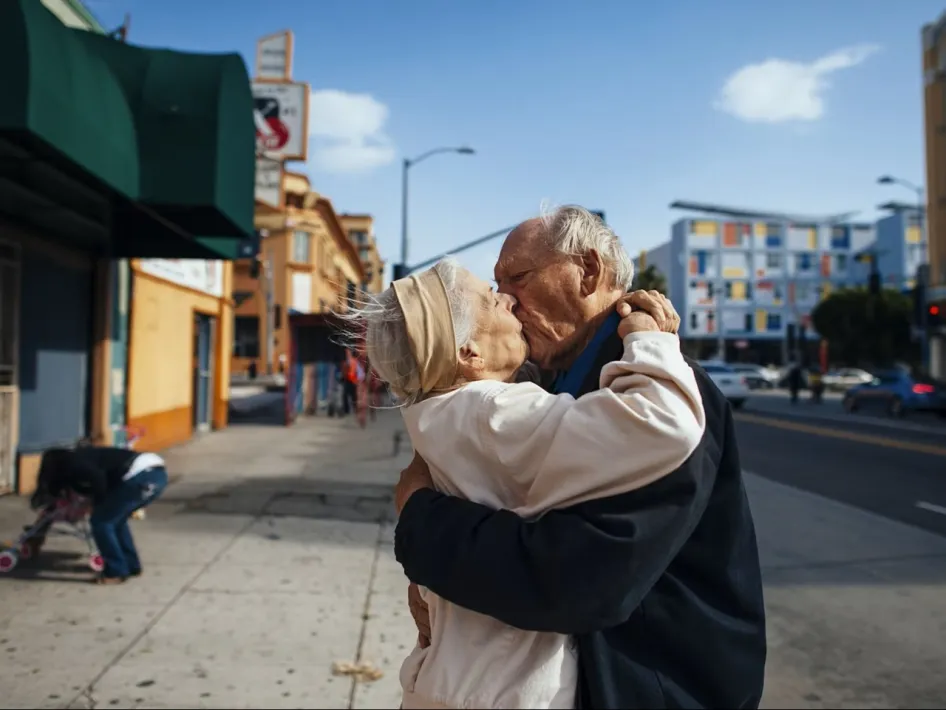 Twee oudere mensen zoenen elkaar op straat, als voorbeeld van het thema van de tentoonstelling Grijs! Art on Aging.