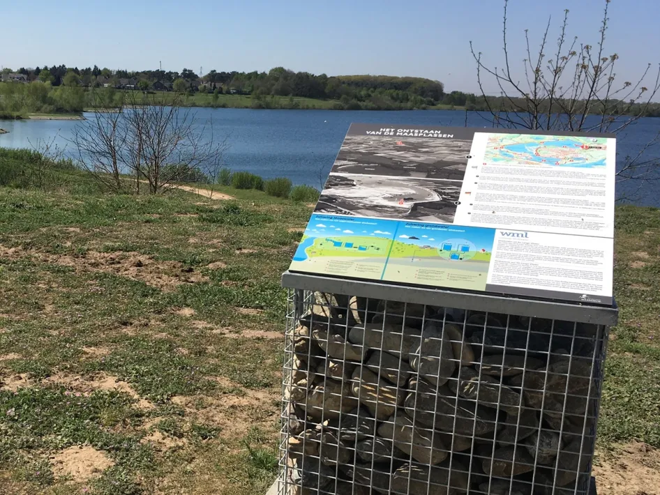 Information board about the origin of the Maas Lakes with a view over the water near Heel