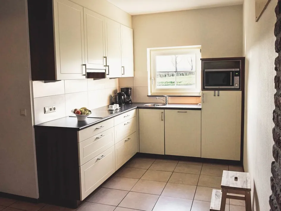 Bright kitchen with white cabinets, black countertop and a window overlooking greenery.