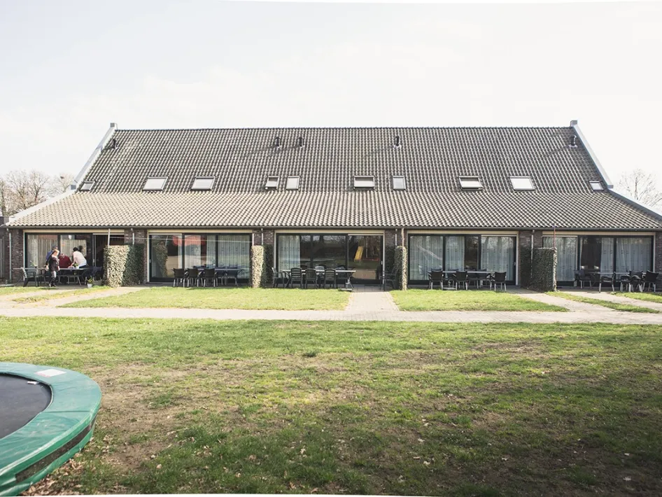 Vorderseite Urlaubsbauernhof Groenslaperij de Cornelishof mit großen Fenstern, Terrassen und grünem Garten.