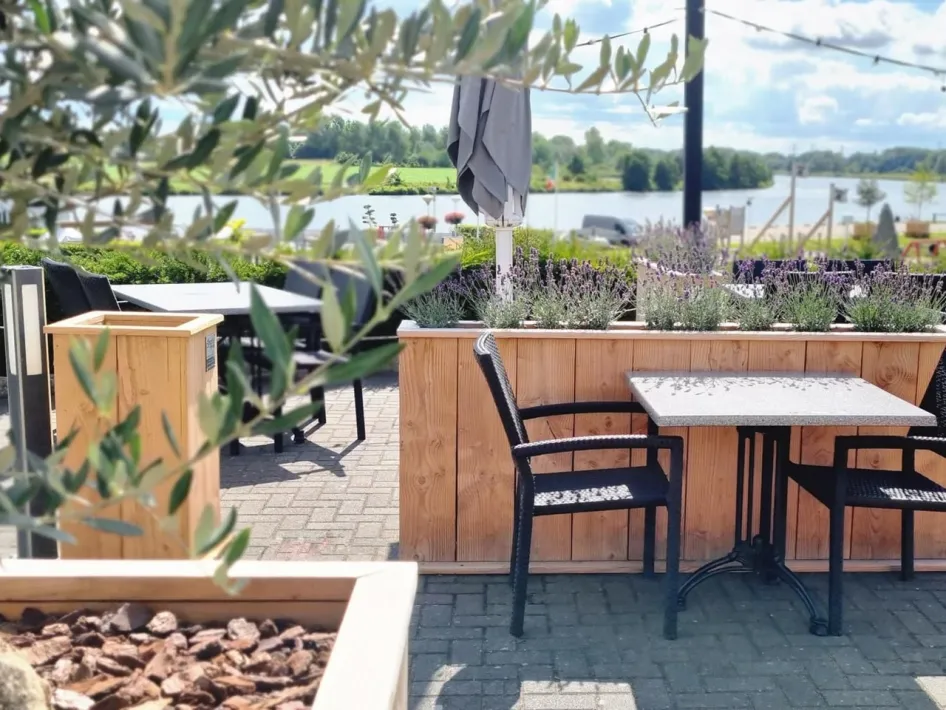 Terras van Heere aan de Maas met tafels, planten en uitzicht over het water.