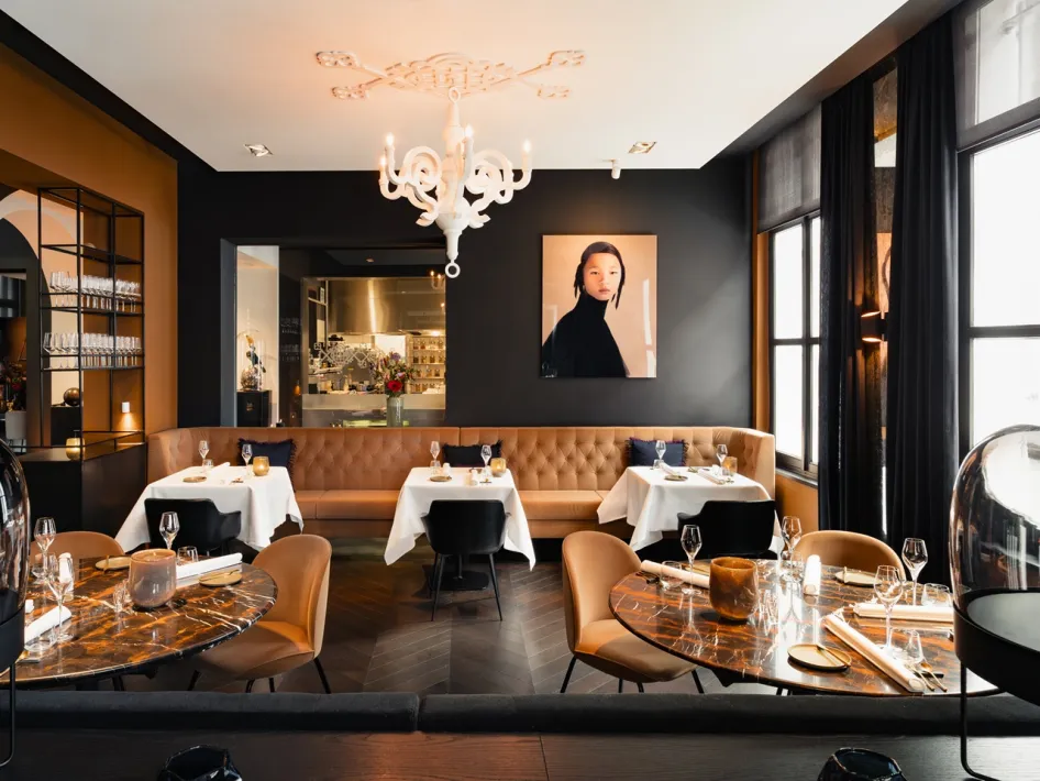 Interieur van restaurant Damianz in Het Arresthuis in Roermond, met gedekte tafels, leren zitbank en moderne verlichting.