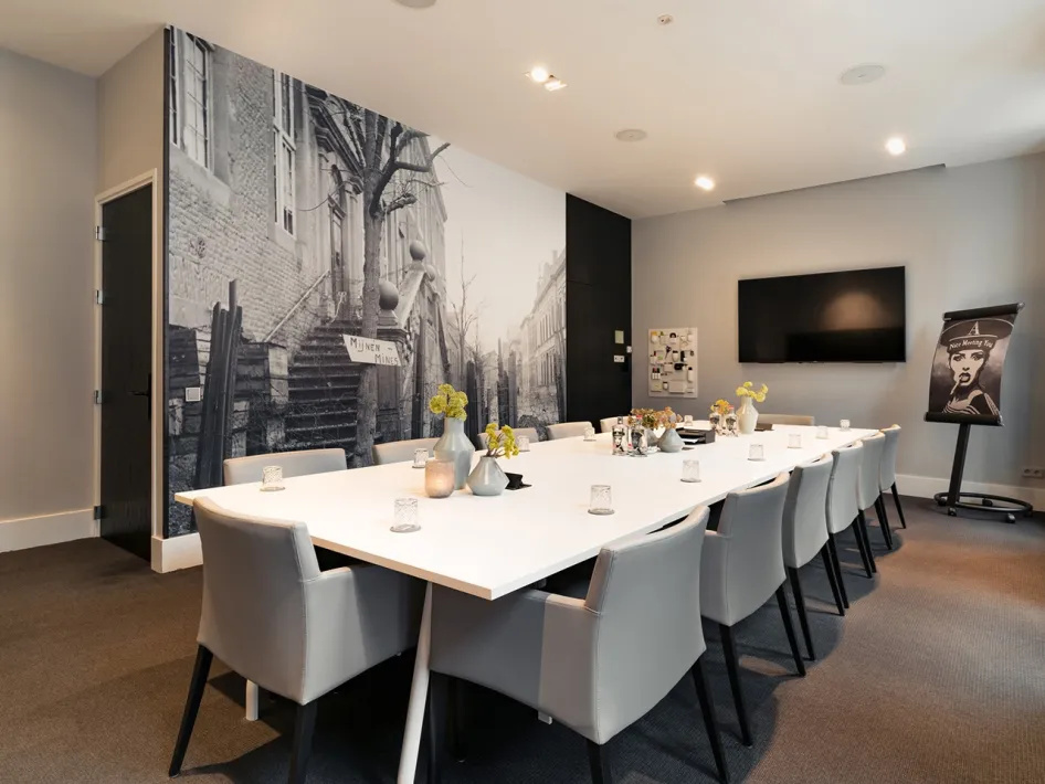 Vergaderzaal De Kracht in Het Arresthuis in Roermond, met een lange vergadertafel, beeldscherm en historische wandfoto.