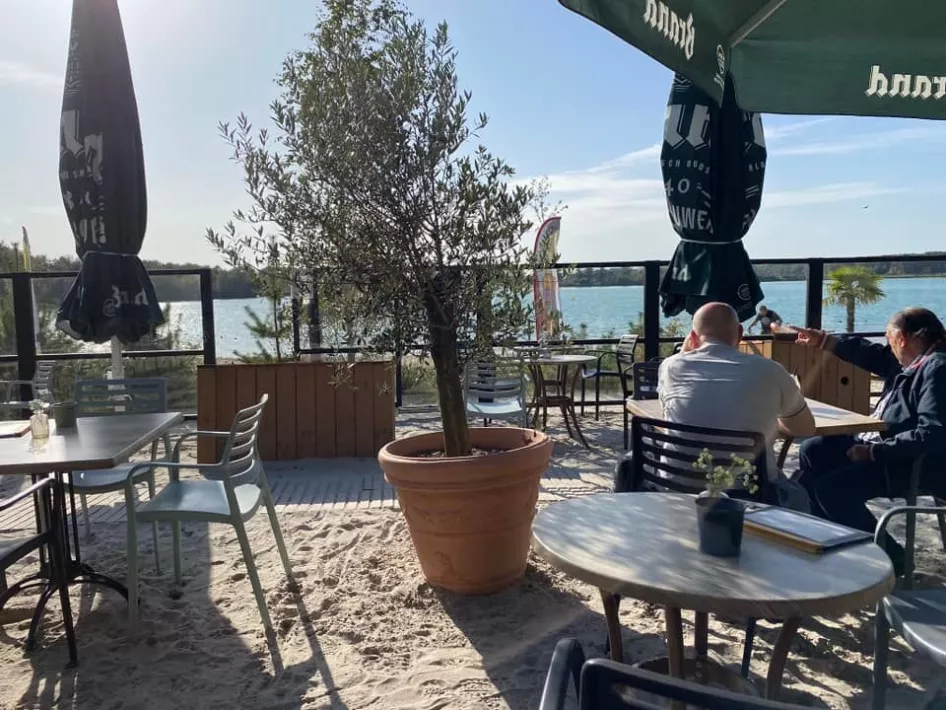 Mensen genieten op het terras met uitzicht op hetPeople enjoying the terrace overlooking Blauwe Meertje