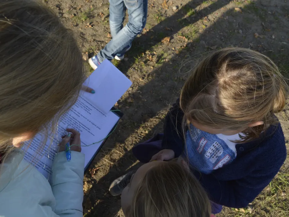 Two girls studying a task sheet during an outdoor GPS based game