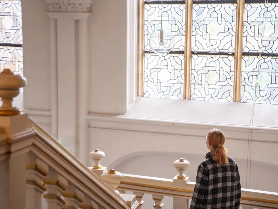 Wandelaar staat in een historisch trappenhuis van de Abdijkerk in Thorn