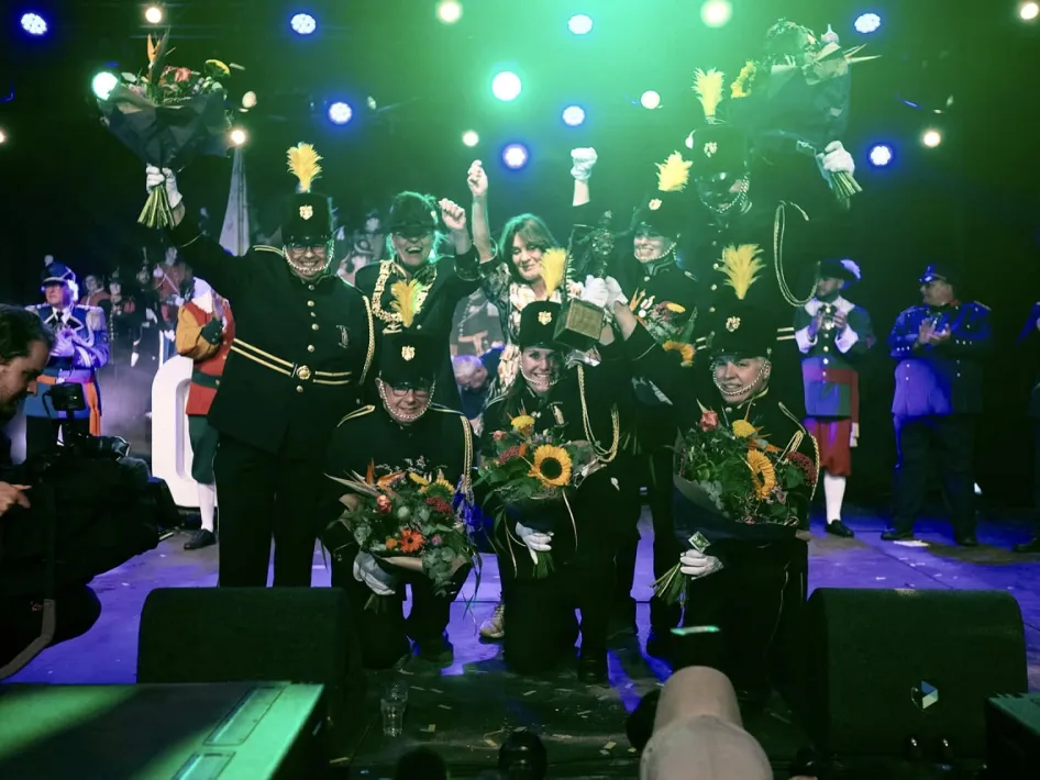 Winnaars vieren feest op de OLS-feestavond, omringd door schutters in traditionele uniformen en een sfeervolle lichtshow.