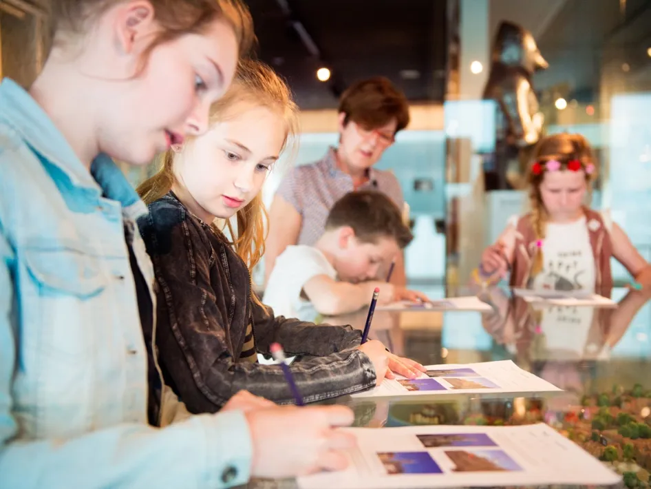 Kinderen werken aan een speurtocht of educatieve opdracht in het Historiehuis Roermond.