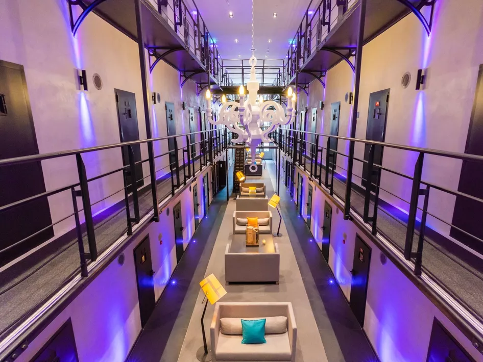 Het iconische cellenblok van Het Arresthuis in Roermond, met luxe inrichting, sfeerverlichting en moderne zitgedeeltes die de historische gevangenis omvormen tot een stijlvol hotel.