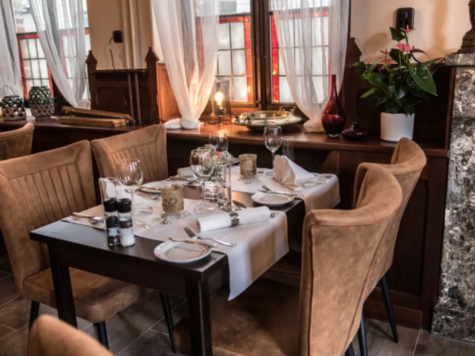 Het restaurant van Hotel Restaurant Crasborn met sfeervol gedekte dinertafel bij de ramen in Thorn.