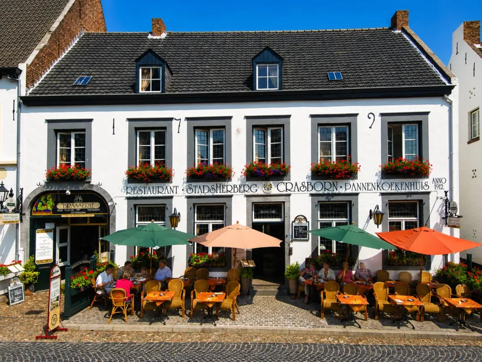Front view of Hotel Restaurant Crasborn on the charming square in the white town of Thorn, featuring a terrace and historic façade.