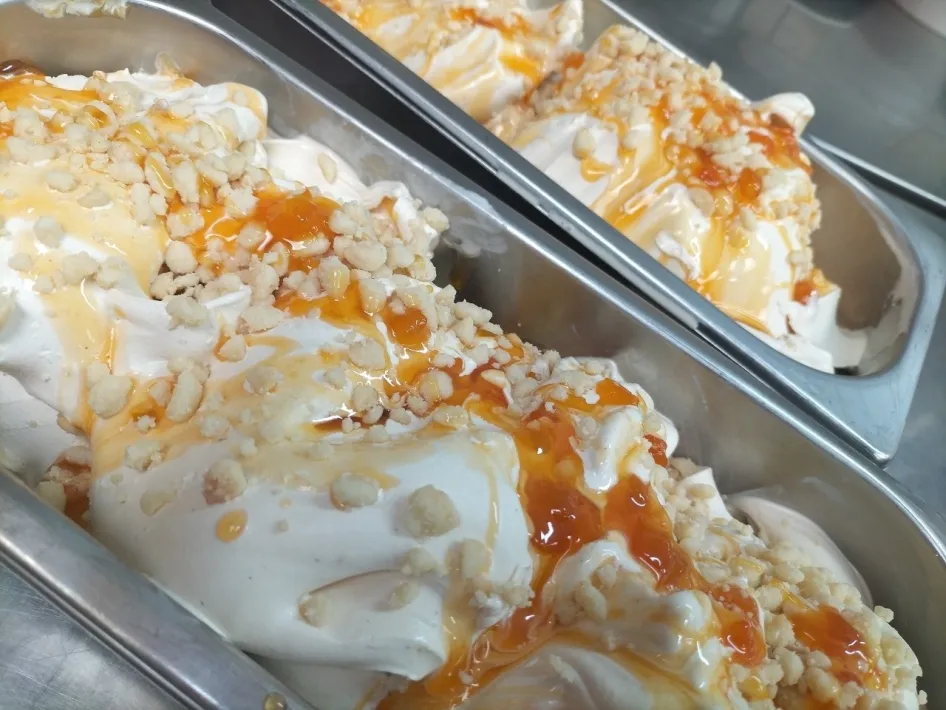 Dairy ice cream with orange sauce and crunchy crumbs in the ice cream display at Ice Cream Parlour Malla Vista.