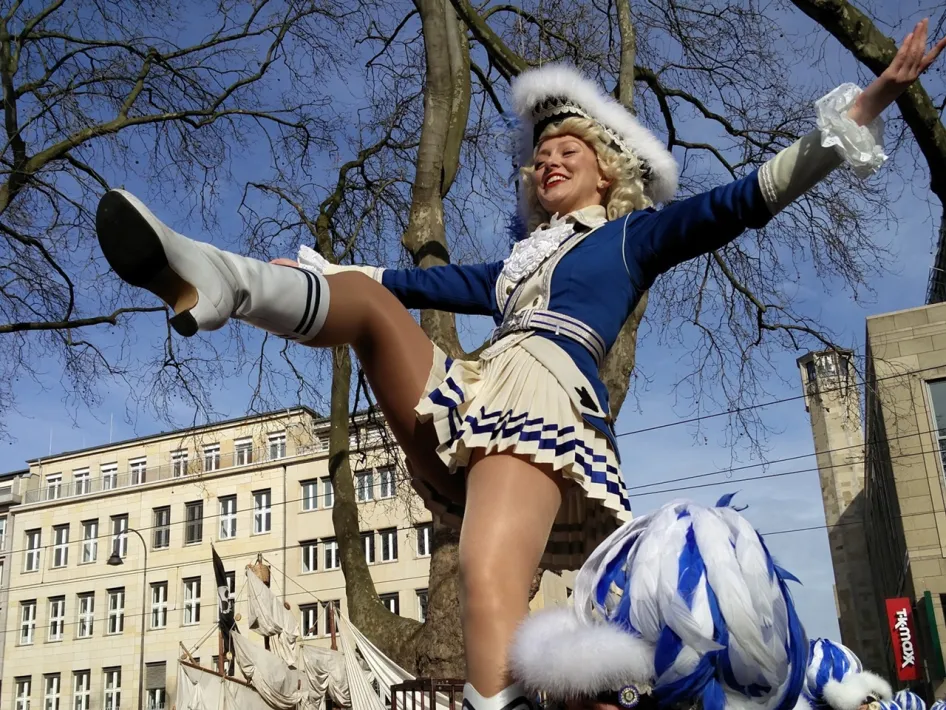 Dansmarieke in blauw-wit kostuum tijdens een carnavalsoptocht, onderdeel van de lezing Carnaval en de Kölner Blauen Funken in het Museum van de Vrouw.