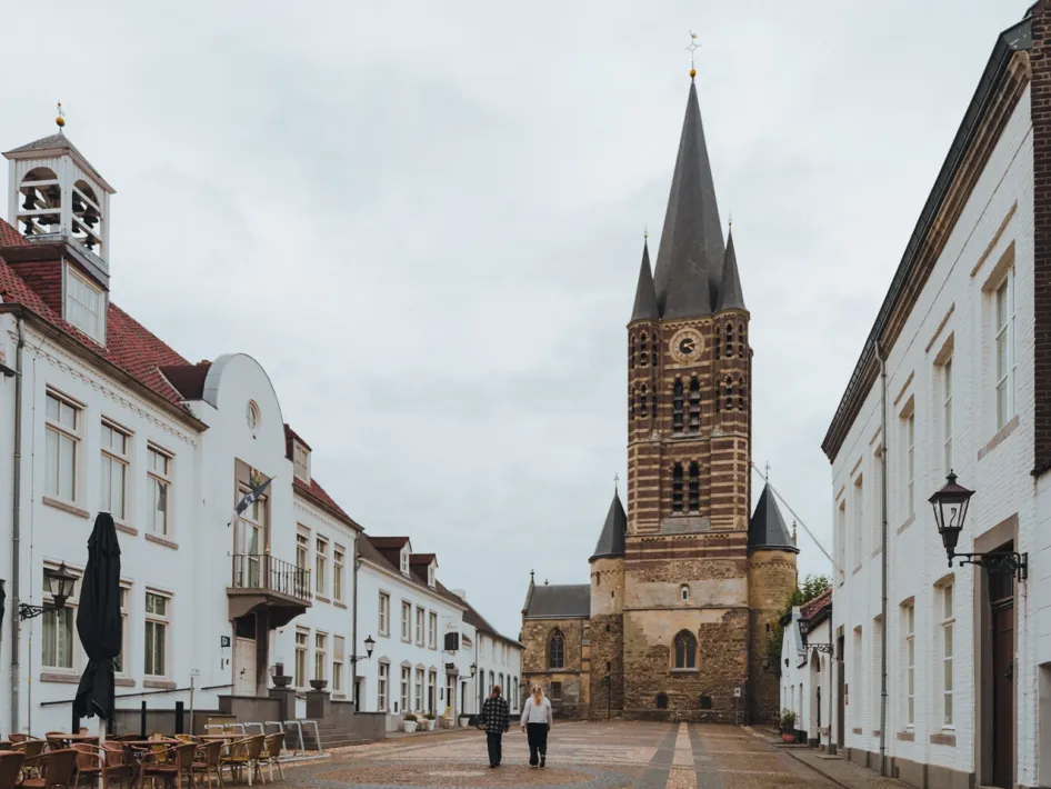 Zwei Wanderer entdecken während des interaktiven Stadtrundgangs durch Thorn das historische Zentrum mit der Abteikirche und den charakteristischen weißen Fassaden.