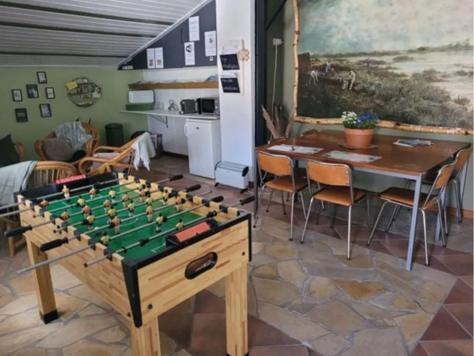 Binnenruimte met keukentje, zitplekken, tafelvoetbal en wanddecoratie op de camping van Kampeerderij De Kaaiewaaier.