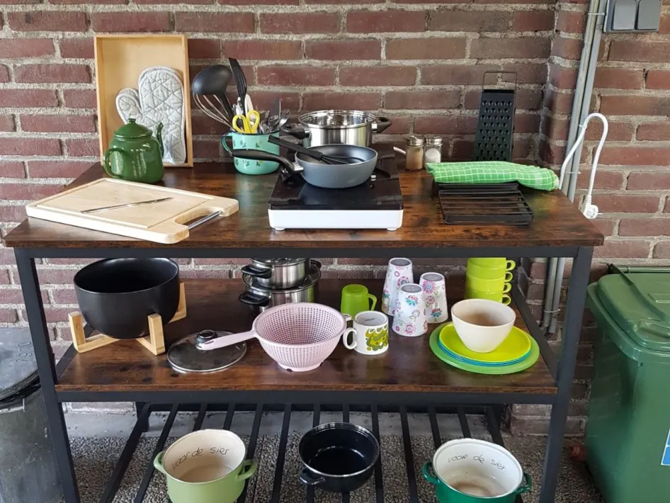 Buitenkeuken met servies, pannen en kookplaat, speciaal ingericht voor tentkampeerders op de camping.