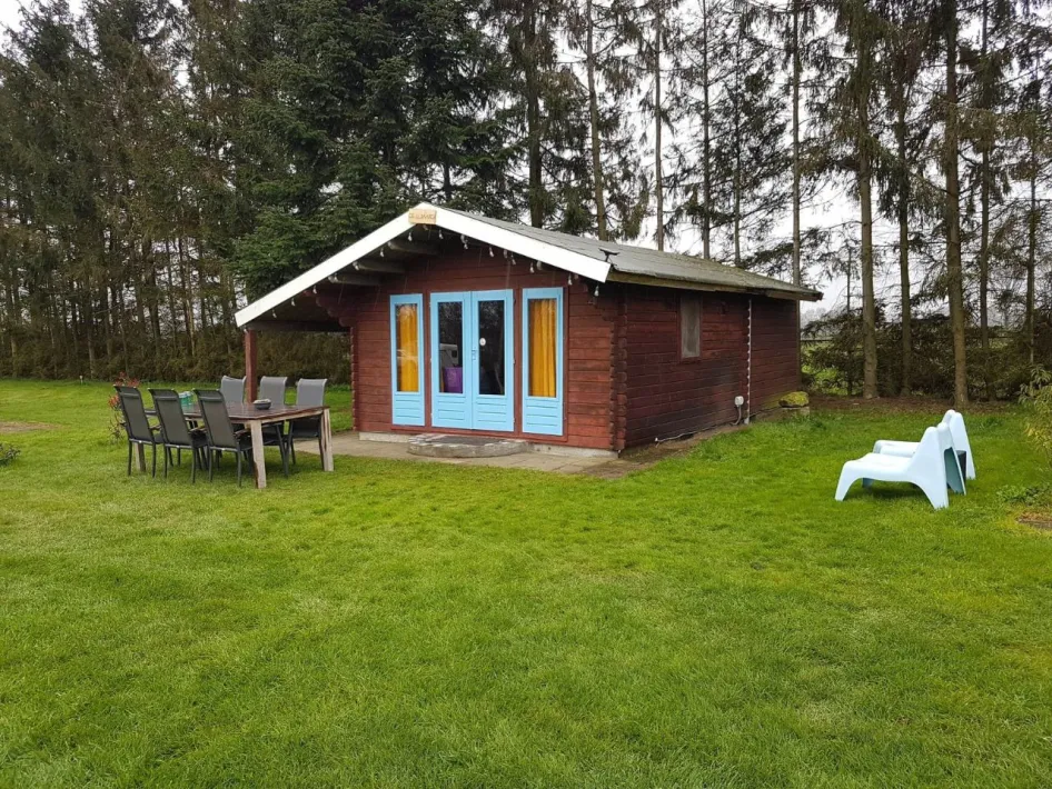 Wooden holiday cottage De Luiwammes with blue doors, terrace, and garden furniture in a green, wooded area.