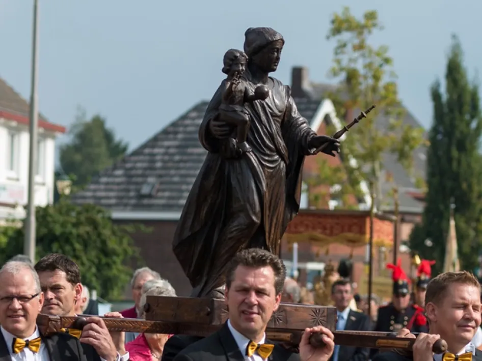 Beeld van de Zwarte Madonna wordt gedragen tijdens de kermisprocessie in Heel, omringd door deelnemers in traditioneel uniform.