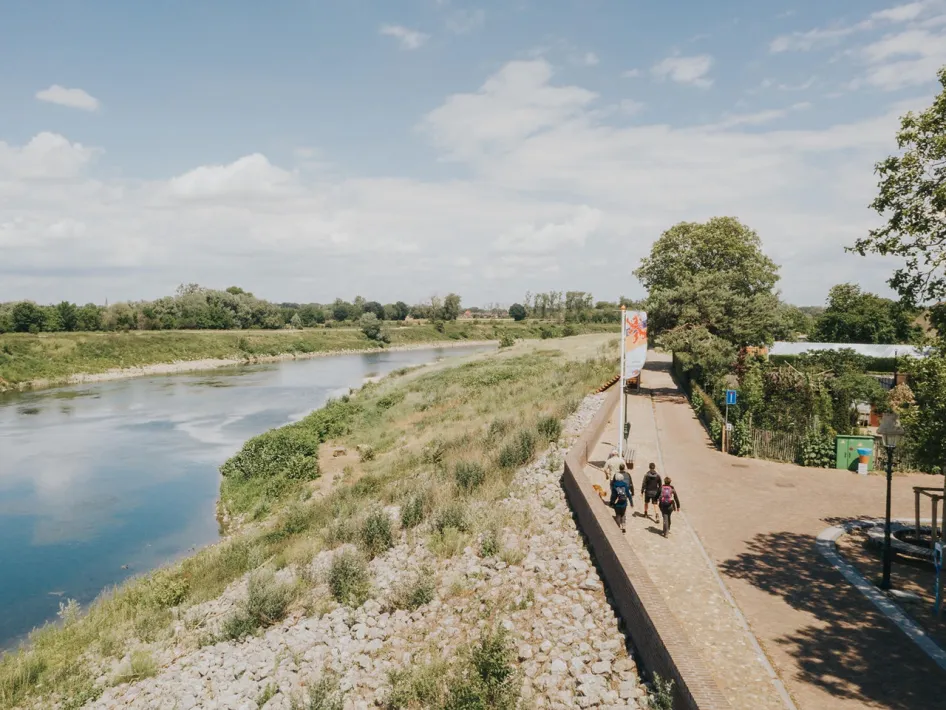 Wandelaars op de dijk langs de Maas tijdens de LAW RivierPark Maasvallei.