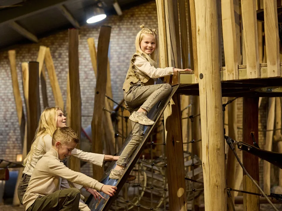Kinder spielen auf einem Holzspielgerät im Indoor-Spielplatz von La Selva.