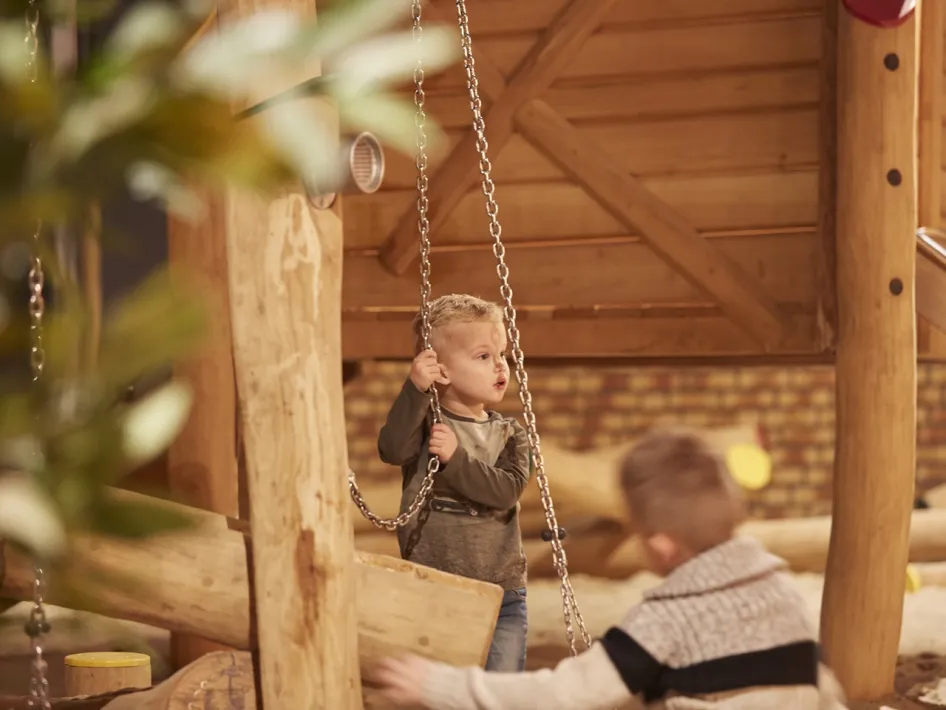 Een kind speelt op een schommel in de indoor speeljungle van La Selva.