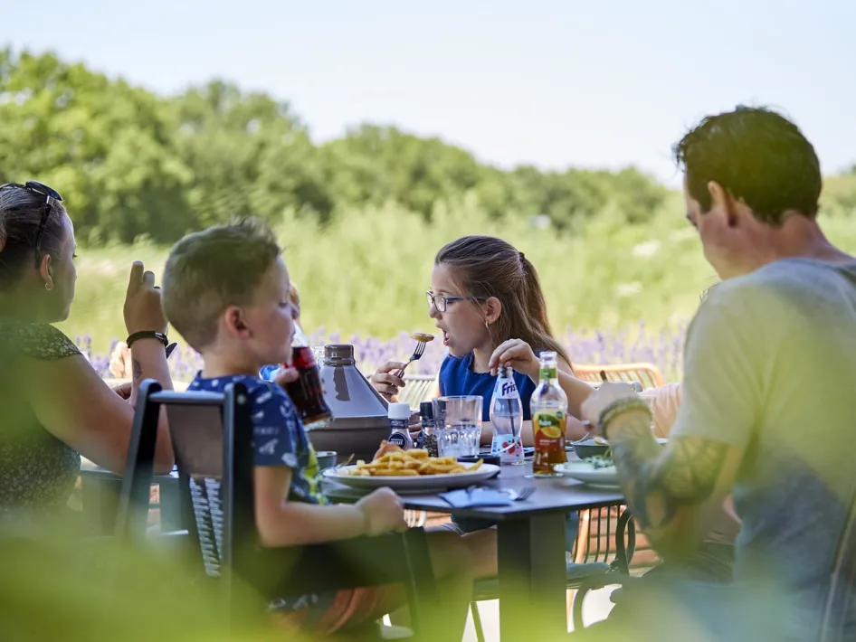Een gezin zit op het terras van La Selva met uitzicht op het groen.