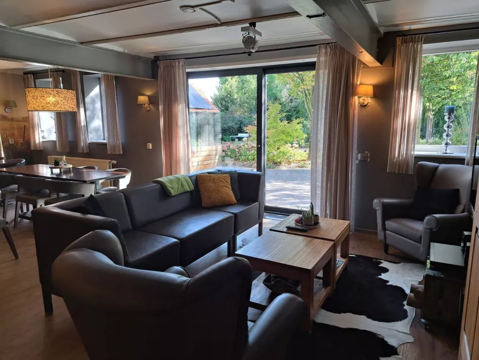 Gezellige woonkamer met zithoek, eethoek en uitzicht op de tuin door grote schuifpui.