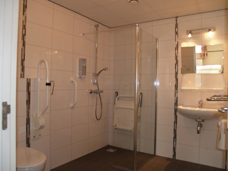 Spacious and adapted bathroom with walk-in shower, wall brackets and seat for extra comfort.