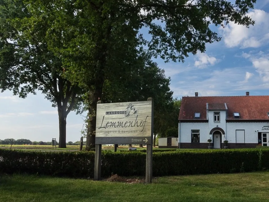 Vooraanzicht van accomodatie n het Limburgse landschap met bord en groene omgeving.