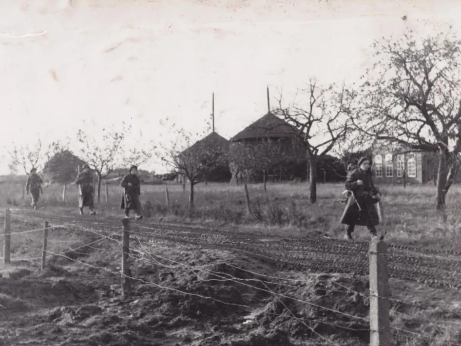 Belgische soldaten van de Brigade Piron lopen gewapend over een modderige landweg bij boerderijen in Thorn.