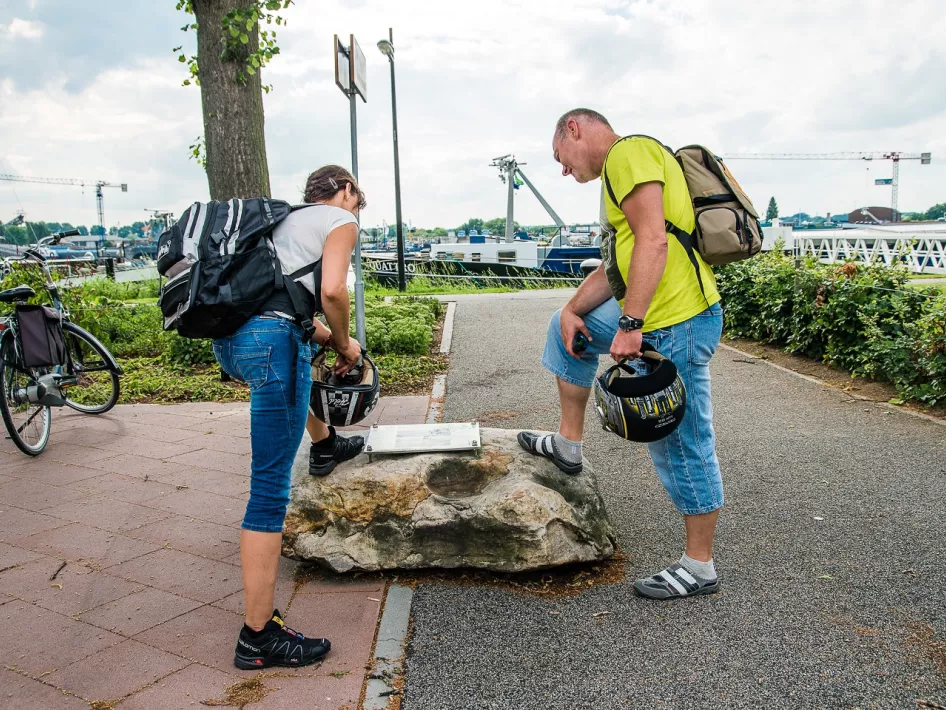 Couple looks at the Liberation Route sign in Maasbracht during the Liberation Cycling Route Roerdalen - Roermond - Maasgouw