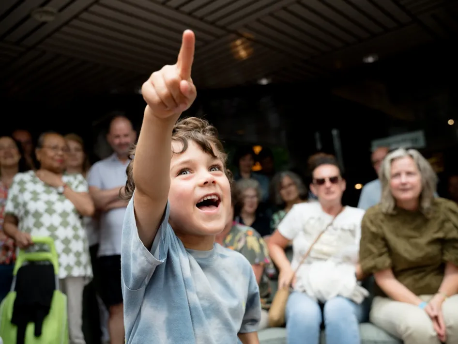 Kind wijst enthousiast omhoog tijdens een kindervoorstelling op Limburg Festival 2025, omringd door publiek.