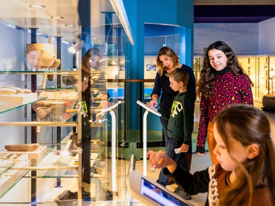 Kinderen bekijken de tablets die bij de vitrines horen