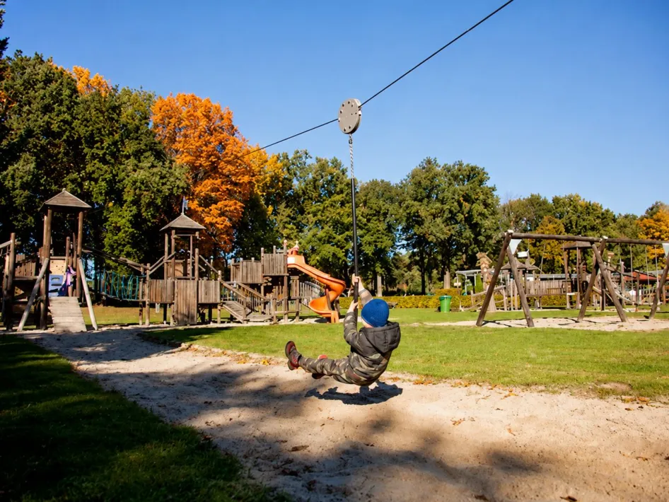Kind auf der Seilbahn zwischen den Spielgeräten im Speeltuin de Gitstap