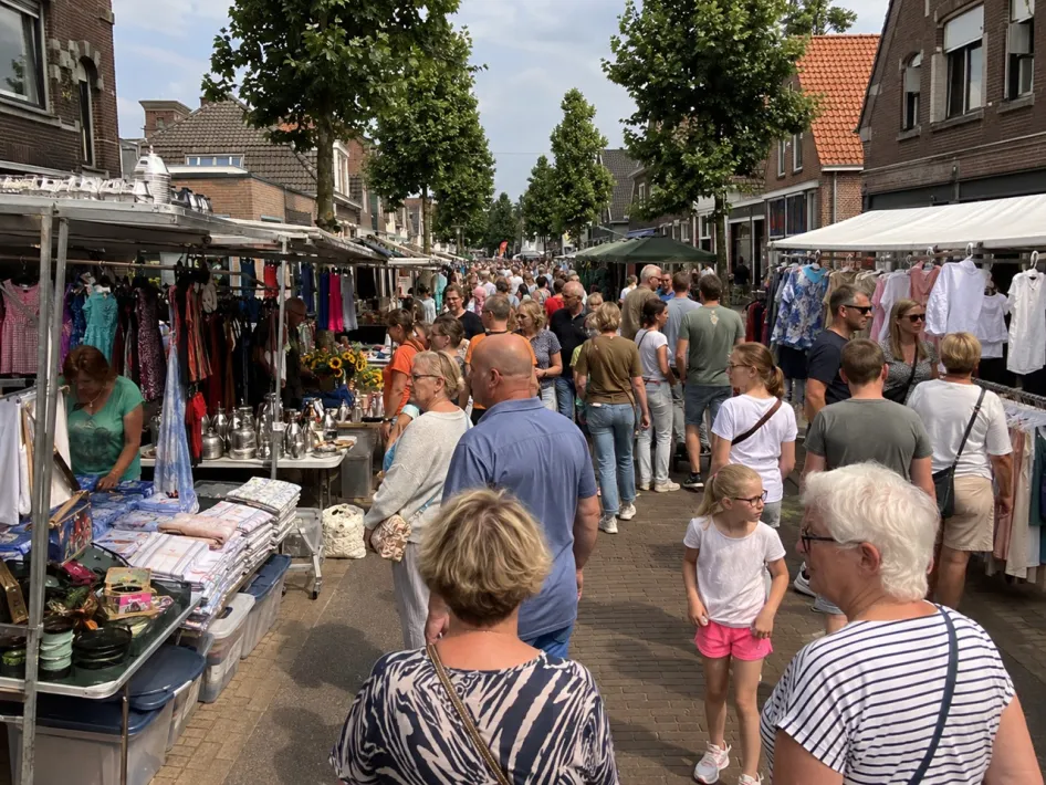 Drukke Luikse markt in Linne met bezoekers tussen marktkramen met kleding, huishoudelijke spullen en andere koopwaar.