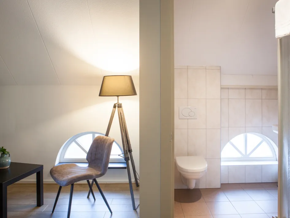 Comfortable hotel room with a seating area, small table and en-suite bathroom.