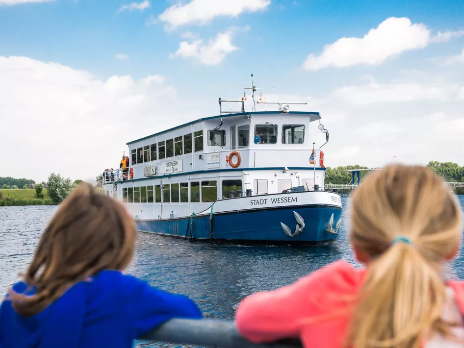 Twee meisjes kijken hoe de rondvaartboot aanmeert voor de rondvaart de Maasparel Tocht