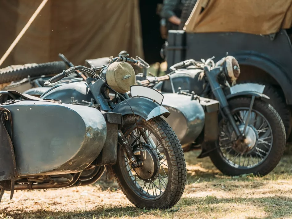 Twee vintage militaire motorfietsen met zijspan op een grasveld tijdens Militracks, een evenement met historische voertuigen.