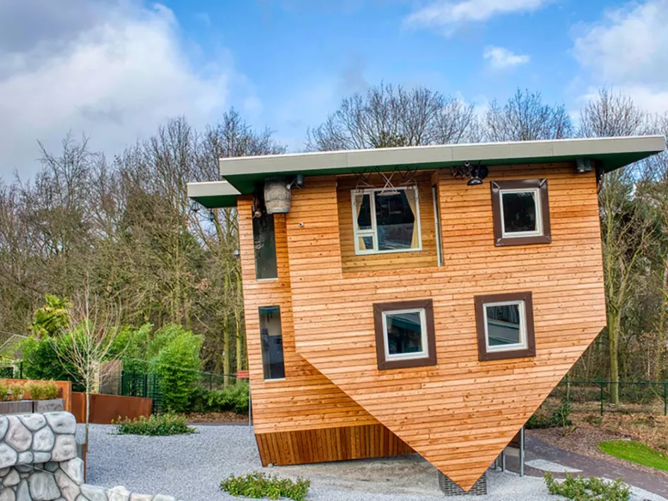 Het iconische 'huis op z’n kop' van Mind Mystery, een houten gebouw dat ondersteboven staat en bezoekers uitnodigt om de illusie te betreden.