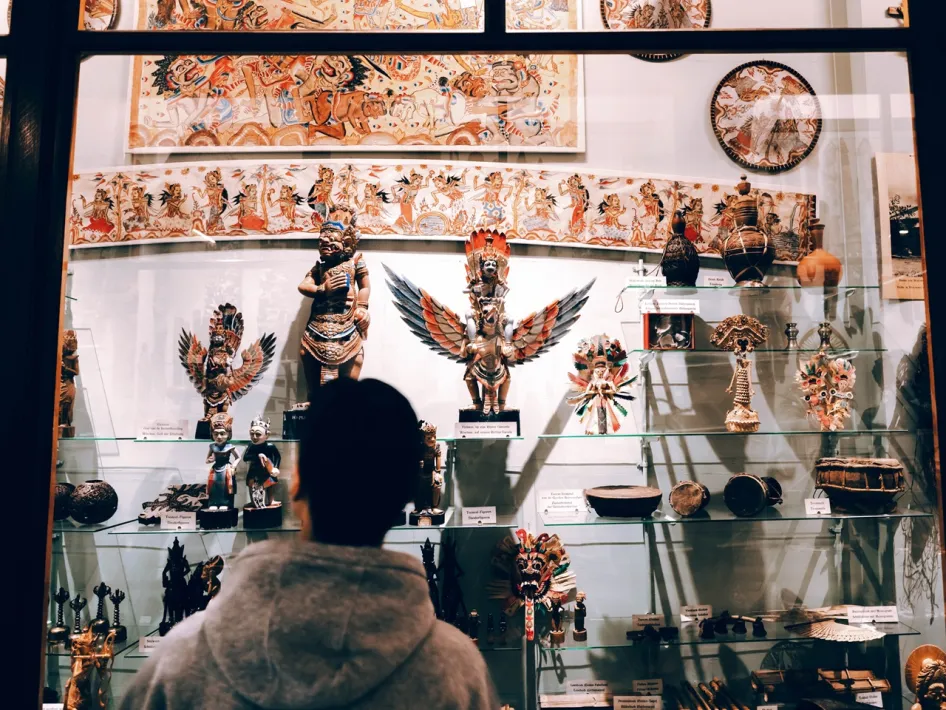 Bezoeker bekijkt een vitrine met beelden, kunstvoorwerpen en andere objecten in Missiemuseum Steyl.