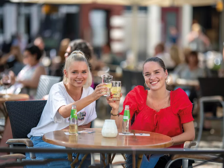 Two women toast with a drink they got for free with the Museum pass voucher Weert