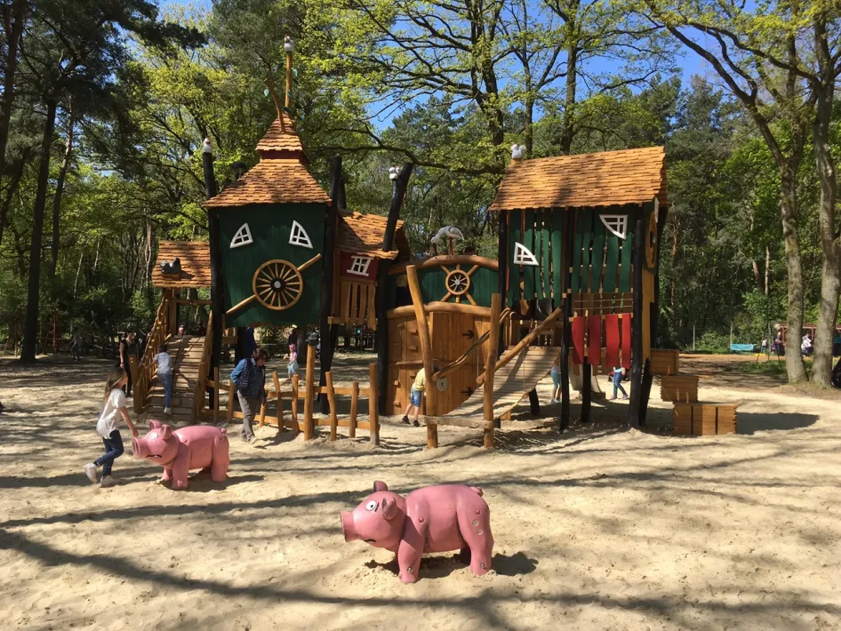 Kinder spielen in einem bunten Holzspielhaus mit Schweinen im Natur- und Tierpark Brüggen