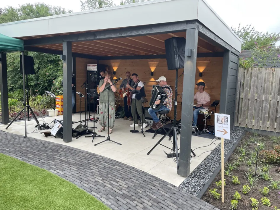 Muzikanten verzorgen een liveoptreden onder een overkapping tijdens Nederweert Live inne hoóf.